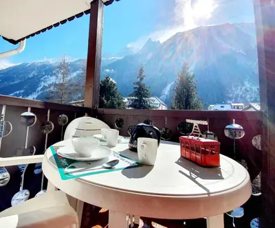a table on a balcony with a view of mountains at La Rivière Vue Mont Blanc in Chamonix-Mont-Blanc