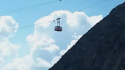 a gondola is flying over a mountain at studio plein sud vue Mont Blanc CHAMONIX in Chamonix-Mont-Blanc