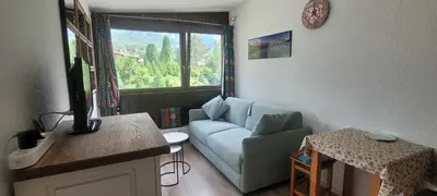 a living room with a blue couch and a window at studio plein sud vue Mont Blanc CHAMONIX in Chamonix-Mont-Blanc