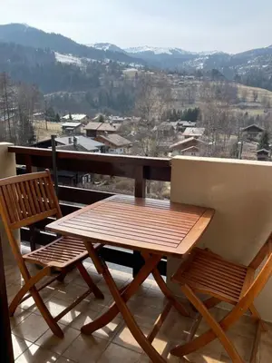 a wooden table and two chairs on a balcony at Studio « Au beau soleil » in Saint-Gervais-les-Bains