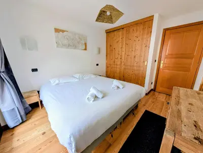 a bedroom with a bed with white sheets and a wooden door at Cham'Heart, 4-star apartments in Chamonix centre with free private parking in Chamonix-Mont-Blanc