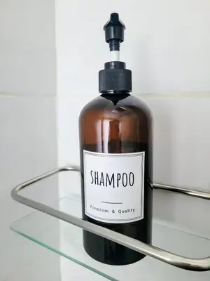 a bottle of shampoo sitting on a glass shelf at Cham'Heart, 4-star apartments in Chamonix centre with free private parking in Chamonix-Mont-Blanc