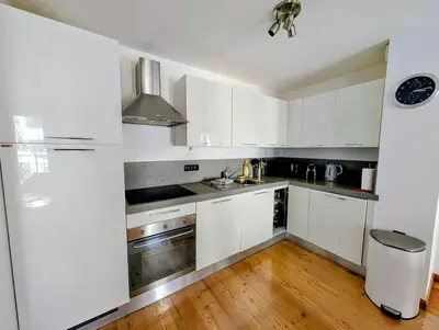 a kitchen with white cabinets and a wooden floor at Cham'Heart, 4-star apartments in Chamonix centre with free private parking in Chamonix-Mont-Blanc