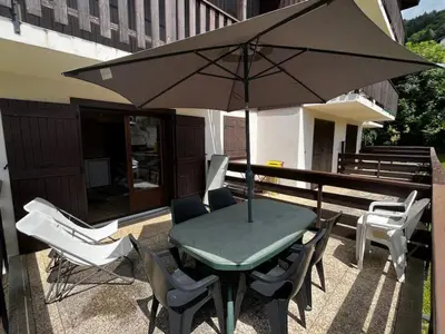 a table and chairs and an umbrella on a patio at Appartement idéal été ou hiver, pour skieurs et promeneurs, 4 personnes in Saint-Gervais-les-Bains