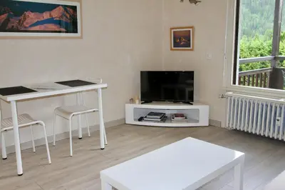 a living room with a white table and a tv at studio residence Grands Montets in Chamonix-Mont-Blanc