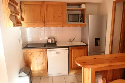 a kitchen with wooden cabinets and a white refrigerator at Le Grand Panorama in Saint-Gervais-les-Bains