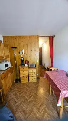 a room with a table and a kitchen with a microwave at Studio pieds des pistes les Houches Vallée de Chamonix in Les Houches