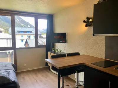 a room with a kitchen with a desk and a window at Studio lumineux neuf dans l'hyper centre avec vue in Chamonix-Mont-Blanc