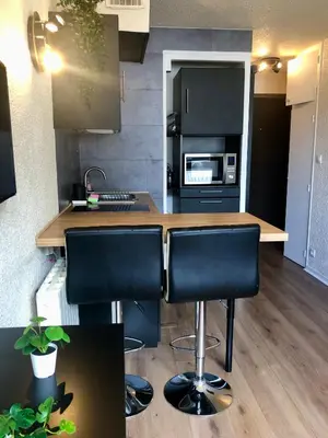 a kitchen with a counter with black chairs in it at Studio lumineux neuf dans l'hyper centre avec vue in Chamonix-Mont-Blanc