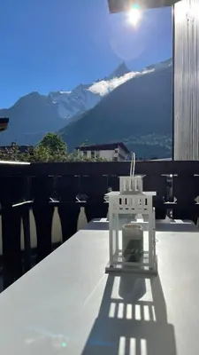 a white chair sitting on a table with a view of mountains at Cosy studio on the slopes and centre of Chamonix in Chamonix-Mont-Blanc