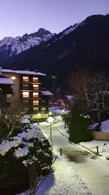 a building with lights on in a snow covered yard at Cosy studio on the slopes and centre of Chamonix in Chamonix-Mont-Blanc