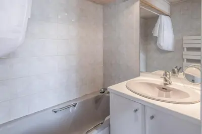 a white bathroom with a sink and a bath tub at Appartement du Mont - Résidence La Vardaffe - Welkeys in Chamonix-Mont-Blanc