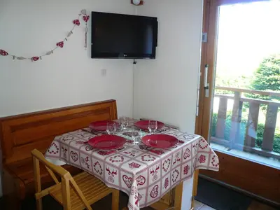 a table with red plates and a television on the wall at Résidence Perle Des Neiges - Perles des Neiges 1 MAE-5319 in Combloux