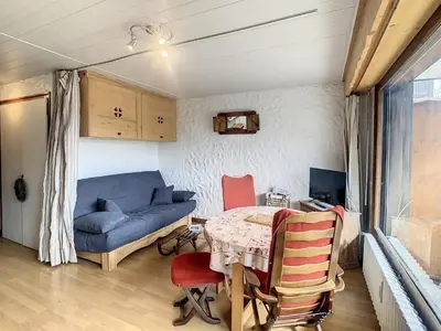a living room with a table and a blue couch at Charmant studio près du centre de Combloux avec kitchenette - FR-1-560-54 in Combloux