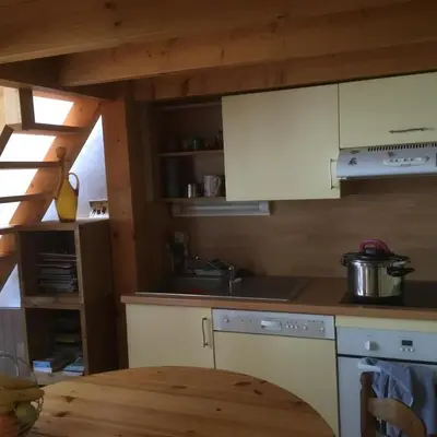 a kitchen with white cabinets and a wooden table at Appartement typique,chaleureux et pratique in Chamonix-Mont-Blanc