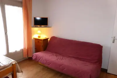 a red couch in a room with a tv on the wall at Résidence Le Royal - Royal 12 MAE-9034 in Combloux