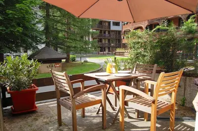 a table and chairs with an umbrella on a patio at L'alpage in Chamonix-Mont-Blanc