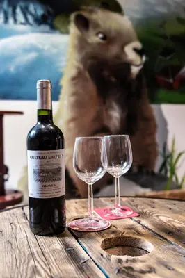 a bottle of wine and two glasses on a wooden table at Le Tête Pied Centre/Télécabine Saint-Gervais in Saint-Gervais-les-Bains