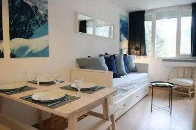a living room with a bed and a table with glasses at Appartement Cosy - Aiguille du Midi in Chamonix-Mont-Blanc