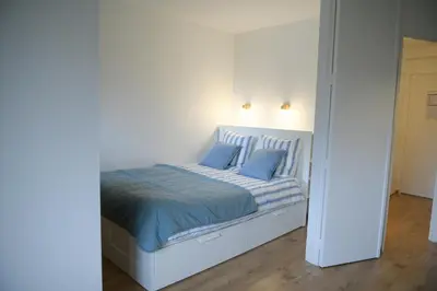 a white bed with blue pillows in a bedroom at Appartement Cosy - Aiguille du Midi in Chamonix-Mont-Blanc