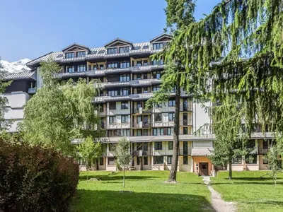 a large apartment building with a park in front of it at Appartement Cosy - Aiguille du Midi in Chamonix-Mont-Blanc
