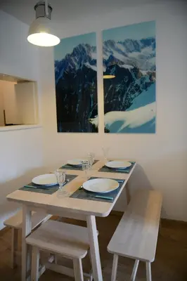 a dining room table with chairs and a painting on the wall at Appartement Cosy - Aiguille du Midi in Chamonix-Mont-Blanc