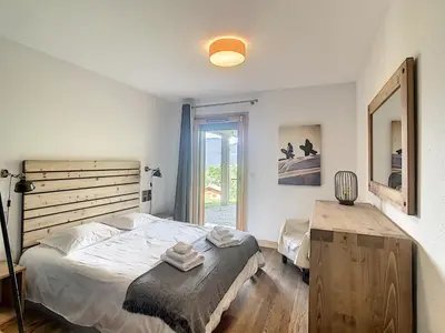 a bedroom with a large bed and a window at Demi-chalet de luxe avec piscine et vue Mont Blanc - FR-1-560-71 in Combloux