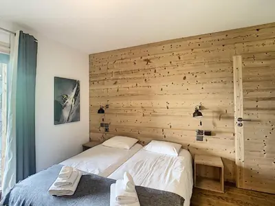 a bedroom with a wooden wall with a bed at Demi-chalet de luxe avec piscine et vue Mont Blanc - FR-1-560-71 in Combloux