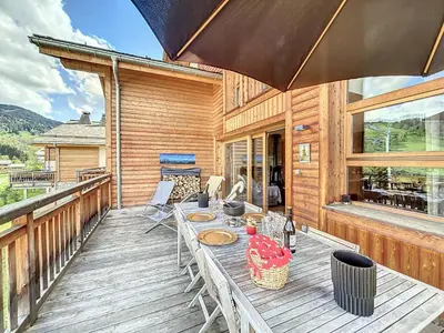 a wooden deck with a table and chairs on it at Demi-chalet de luxe avec piscine et vue Mont Blanc - FR-1-560-71 in Combloux