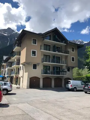 a large building with cars parked in a parking lot at Grey Squirrel Home in Chamonix-Mont-Blanc