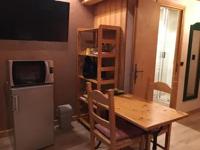 a kitchen with a table and a microwave and a refrigerator at Le Battieu in Samoëns