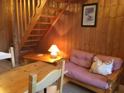 a living room with a couch and a wooden staircase at Le Battieu in Samoëns