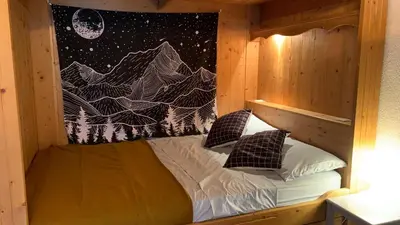 a small bed in a wooden cabin with a mural of mountains at Appartement vue Montblanc 5mn piste1 in Les Houches