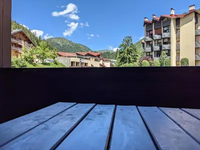 a wooden table on a balcony with a view of a building at Duplex Argentière, 50m2, 6 pers, idéalement placé in Chamonix-Mont-Blanc