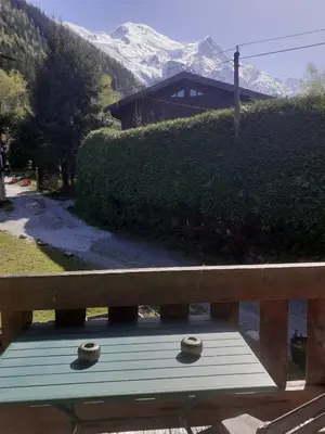 a wooden bench with a view of a snow covered mountain at Appartement La Suite Mont-Blanc in Chamonix-Mont-Blanc
