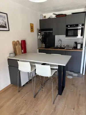 a kitchen with a large white table and white chairs at Location studio plein centre Les Carroz in Les Carroz d'Araches