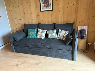 a couch with many pillows on it in a room at Location studio plein centre Les Carroz in Les Carroz d'Araches