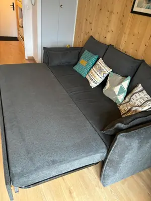 a black couch with pillows on top of it at Location studio plein centre Les Carroz in Les Carroz d'Araches