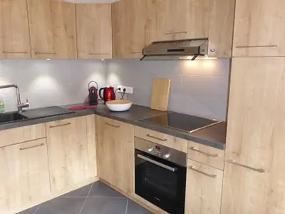 a kitchen with wooden cabinets and a black oven at Duplex Moderne au Centre avec Balcon, 6 Pers. - FR-1-629-13 in Samoëns