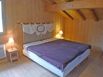 a bedroom with a large bed in a wooden room at Chalet spacieux 12 pers, animaux admis, parking, Wi-Fi - FR-1-629-1 in Samoëns