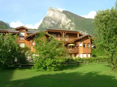 a large house with a mountain in the background at Appartement spacieux 3 pièces avec balcon et garage à Samoëns - FR-1-629-17 in Samoëns