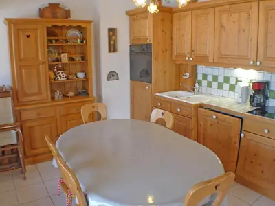 a kitchen with a white table and wooden cabinets at Appartement spacieux 3 pièces avec balcon et garage à Samoëns - FR-1-629-17 in Samoëns