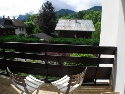 two chairs on a balcony with a view of a house at Appartement lumineux 2 pièces cabine, animaux admis, proche centre Samoëns - FR-1-629-22 in Samoëns
