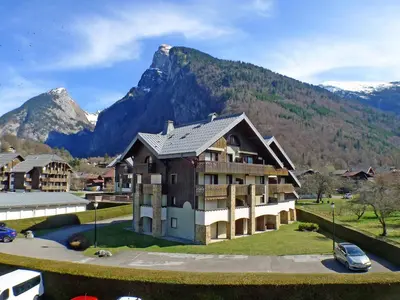 a large building with a mountain in the background at Appartement 2 pièces avec animaux admis, balcon et garage - FR-1-629-27 in Samoëns