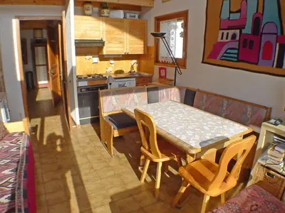 a living room with a table and a kitchen at Appartement calme à Samoëns, 2 chambres, animaux admis, proche centre - FR-1-629-24 in Samoëns