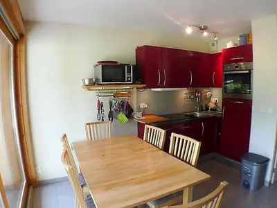 a kitchen with a wooden table and a kitchen with red cabinets at 3 pièces calme à Samoëns avec parking privé, 4 couchages - FR-1-629-48 in Samoëns