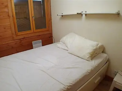 a small bedroom with a white bed with a window at 3 pièces calme à Samoëns avec parking privé, 4 couchages - FR-1-629-48 in Samoëns