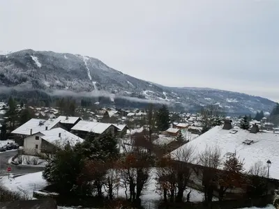 a village covered in snow with a mountain in the background at Appartement 3 pièces avec balcon et parking à Samoëns - FR-1-629-52 in Samoëns
