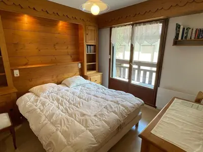 a bedroom with a large bed with a wooden wall at Appartement 3 pièces à Samoëns, 6 pers., WIFI, Parking - FR-1-629-76 in Samoëns