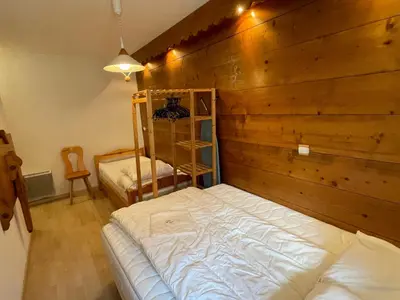 a bedroom with a bed and a wooden wall at Appartement 3 pièces à Samoëns, 6 pers., WIFI, Parking - FR-1-629-76 in Samoëns